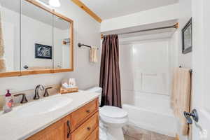 Full bath with vanity, shower / tub combo with curtain, tile patterned floors, and toilet