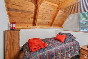 Bedroom with lofted ceiling with beams, wood finished floors, and wooden ceiling