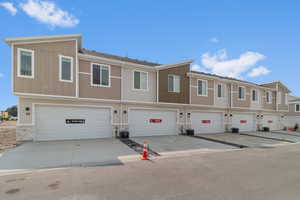 View of front of property with board and batten siding, central AC unit, an attached garage, and stone siding