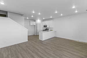 Kitchen featuring stainless steel appliances, baseboards, recessed lighting, white cabinetry, and a peninsula