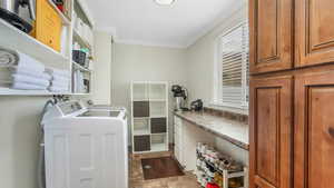 Laundry area with independent washer and dryer, crown molding, and cabinet space