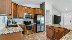 Kitchen featuring a sink, appliances with stainless steel finishes, tasteful backsplash, and lofted ceiling