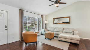 Living room with baseboards, ceiling fan, vaulted ceiling, and wood finished floors