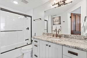 Bathroom with vanity, combined bath / shower with glass door, toilet, and visible vents