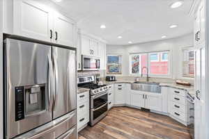 Kitchen featuring recessed lighting, a sink, white cabinetry, and stainless steel appliances