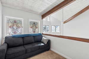 Living room featuring vaulted ceiling with beams, baseboards, and carpet floors