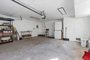 Garage featuring electric panel, a garage door opener, and visible vents