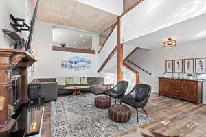 Living area featuring a fireplace with raised hearth, stairs, wood finished floors, and wood ceiling