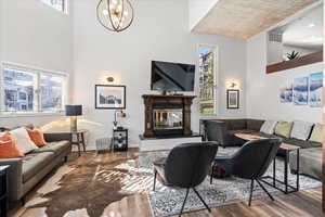 Living area with visible vents, a towering ceiling, wood finished floors, and a chandelier