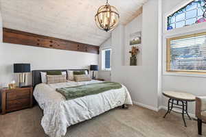 Bedroom featuring lofted ceiling, baseboards, wood ceiling, carpet flooring, and a notable chandelier