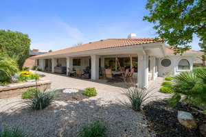 Back of property featuring a patio, a chimney, stucco siding, and a tile roof
