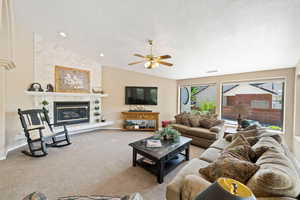 Carpeted living area with a textured ceiling, vaulted ceiling, ceiling fan, and visible vents