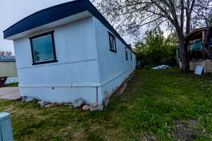 View of property exterior featuring a lawn and fence