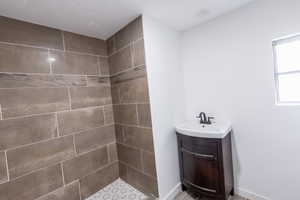 Full bathroom with vanity, baseboards, and a tile shower