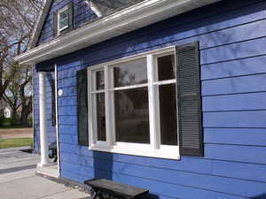 View of side of home and historic wooden window from the outside looking into the living room of White door unit 2