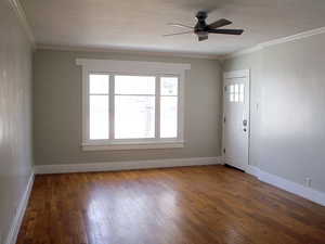 White door unit 2 living room with crown molding, beautiful wooden floors and the large historic wooden window looking to the outside.
