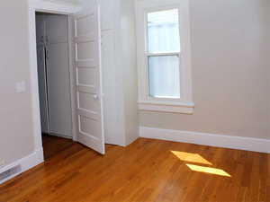 Bedroom #1 with two windows, wood finished floors, and baseboards and ornate crown molding  in White Door unit 2.