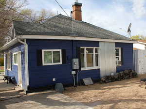 Back of house featuring a newly shingled roof, a chimney, future water feature and shipping container.