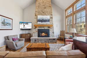Living area featuring a fireplace, wood finished floors, and high vaulted ceiling