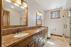 Bathroom featuring double vanity, a sink, toilet, and a shower stall