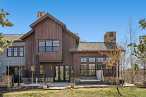 Rear view of property featuring french doors, central AC, a chimney, and stone siding