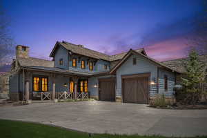 View of front facade featuring a porch, driveway, a chimney, and a garage