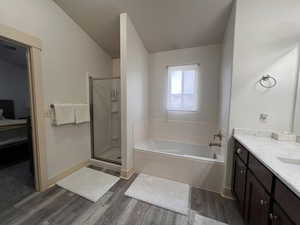 Bathroom with vanity, baseboards, wood finished floors, a bath, and a stall shower