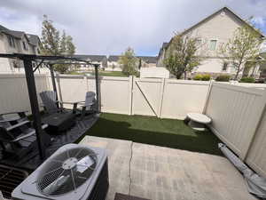 View of patio with a fenced backyard, central AC, and turf