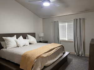 Carpeted bedroom with ceiling fan and vaulted ceiling