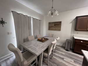 Dining room with baseboards, a chandelier, and light wood finished floors