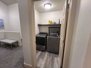 Washroom with independent washer and dryer, laundry area, baseboards, and wood finished floors