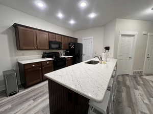 Kitchen featuring visible vents, a sink, light wood finished floors, and black appliances