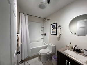 Full bath with toilet, tile patterned floors, shower / bath combination with curtain, and vanity
