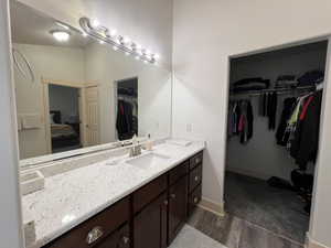 Ensuite bathroom featuring a walk in closet, ensuite bath, vanity, baseboards, and wood finished floors