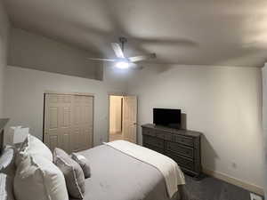 Bedroom featuring ceiling fan, vaulted ceiling, baseboards, a closet, and carpet