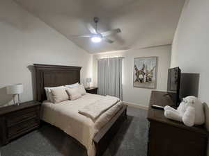 Bedroom with a ceiling fan, baseboards, vaulted ceiling, and dark carpet