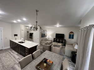 Kitchen with dark brown cabinetry, a sink, light wood finished floors, black dishwasher, and a peninsula