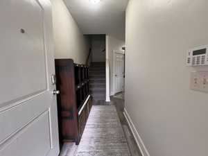 Hallway featuring baseboards, stairs, and wood finished floors
