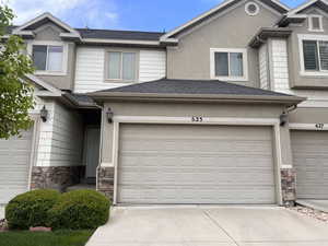 Townhome / multi-family property featuring an attached garage, concrete driveway, stucco siding, and stone siding