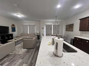 Kitchen with dark wood-style flooring, dark brown cabinets, an inviting chandelier, a sink, and open floor plan