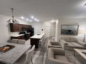 Living room featuring dark wood-type flooring, baseboards, a notable chandelier, and visible vents