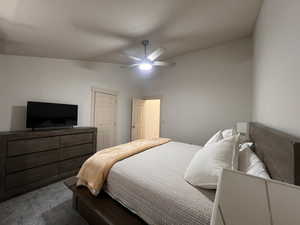 Bedroom featuring a ceiling fan, dark colored carpet, and lofted ceiling