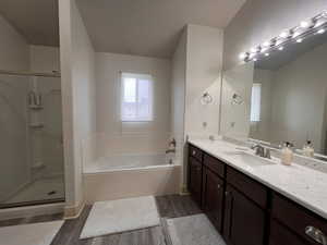 Full bath with a bath, vanity, a shower stall, and wood finished floors