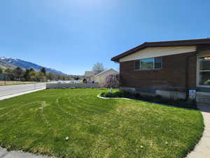 Exterior space featuring brick siding, a mountain view, and a yard