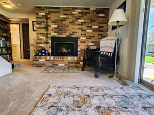 Carpeted living room featuring a textured ceiling and a brick fireplace