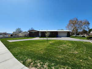 Ranch-style house featuring a garage, a residential view, driveway, and a front yard