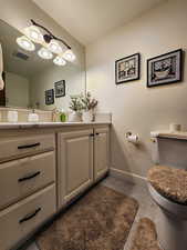 Half bathroom featuring visible vents, tile patterned flooring, vanity, baseboards, and toilet