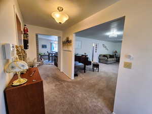Hallway featuring a textured ceiling, baseboards, and carpet