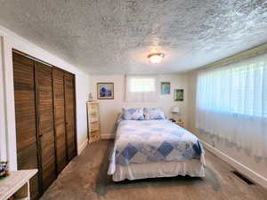 Bedroom featuring baseboards, a closet, a textured ceiling, and visible vents