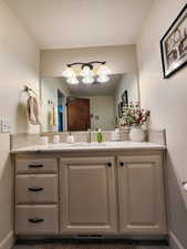 Bathroom featuring vanity, baseboards, and a notable chandelier